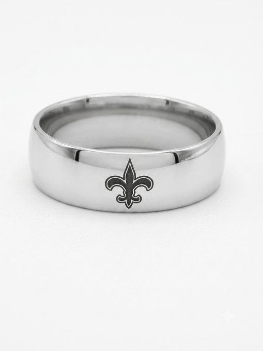 A silver-toned metal band ring featuring a black fleur-de-lis logo on the front, photographed against a clean white background.